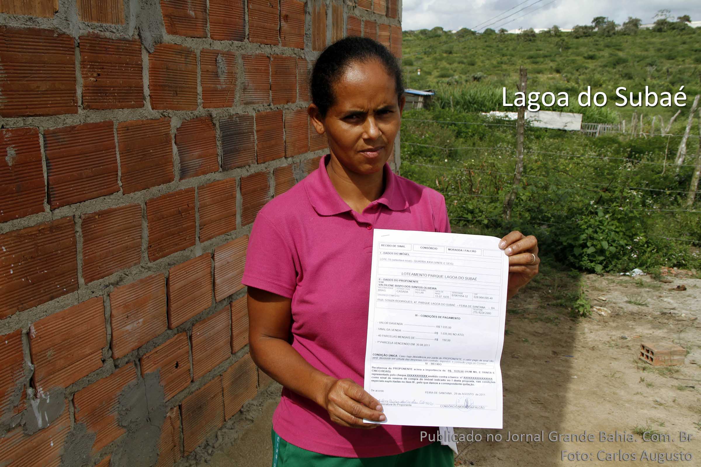 Valdilene Bispo mora a poucos metros da Lagoa do Subaé. Nas mãos, o contrato de compra que tem como vendedores o Consórcio Moradda/Falcão, de Everto Cerqueira e Wilson Falcão. (Foto: Carlos Augusto | Jornal Grande Bahia)