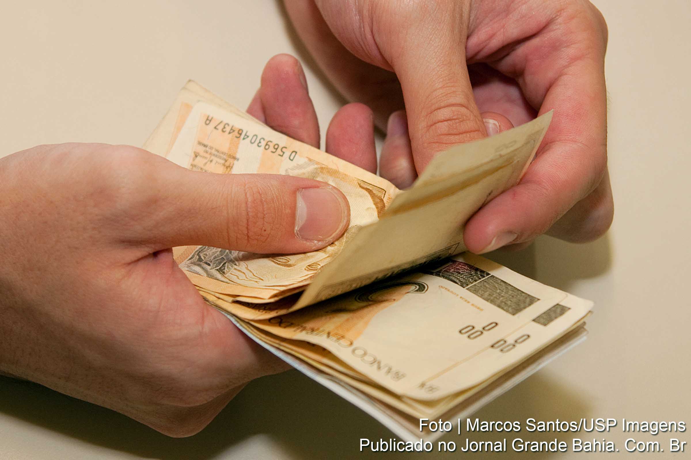 Pessoa manuseia dinheiro e conta cédulas de R$ 50,00 (cinquenta reais).