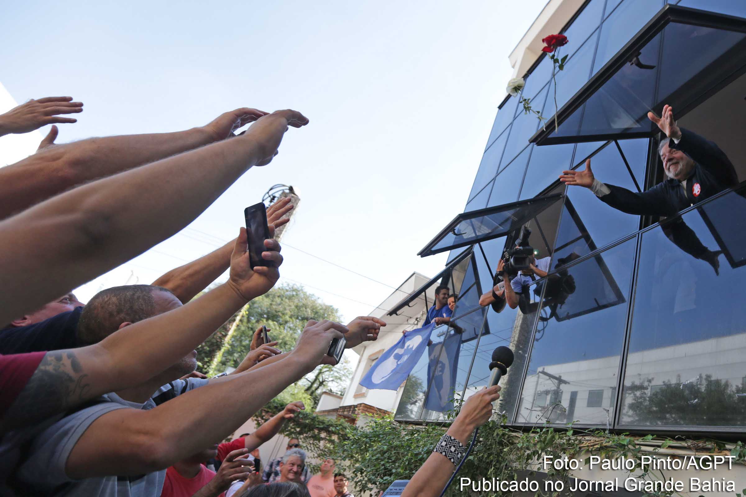 Da janela do Instituto Lula, o ex-presidente joga rosas para militantes.