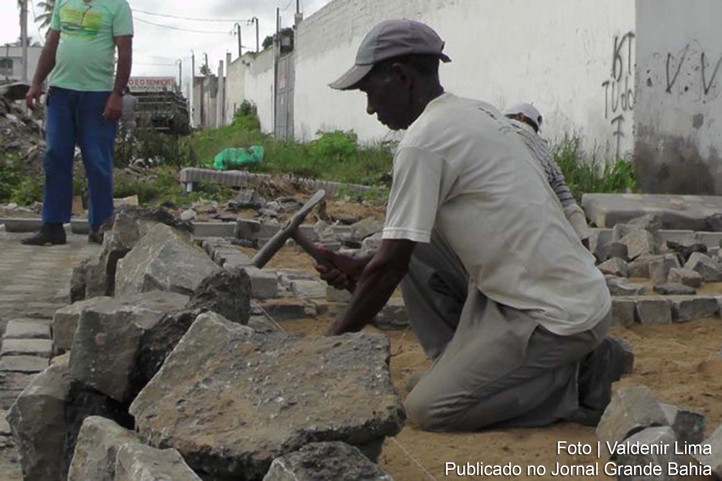 Trabalhador realiza pavimentação de rua à paralelepípedo.