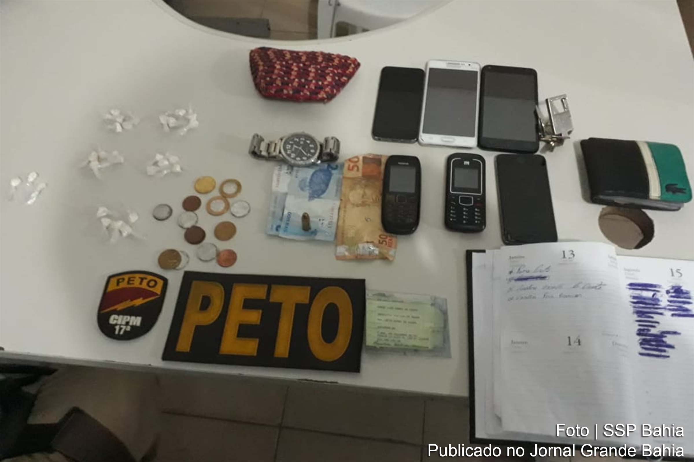 Policiais apreendem trouxas de cocaína, celulares, uma munição de nove milímetros, dinheiro e uma agenda com anotações do tráfico.