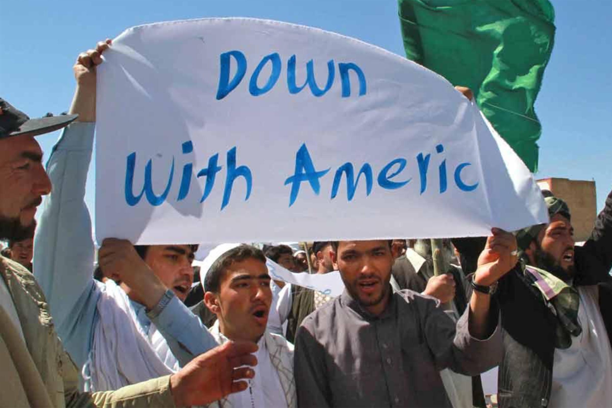 Afegão seguram cartazes em protestos que terminaram em violência, e deixaram onze pessoas mortas, oito delas funcionários da ONU.