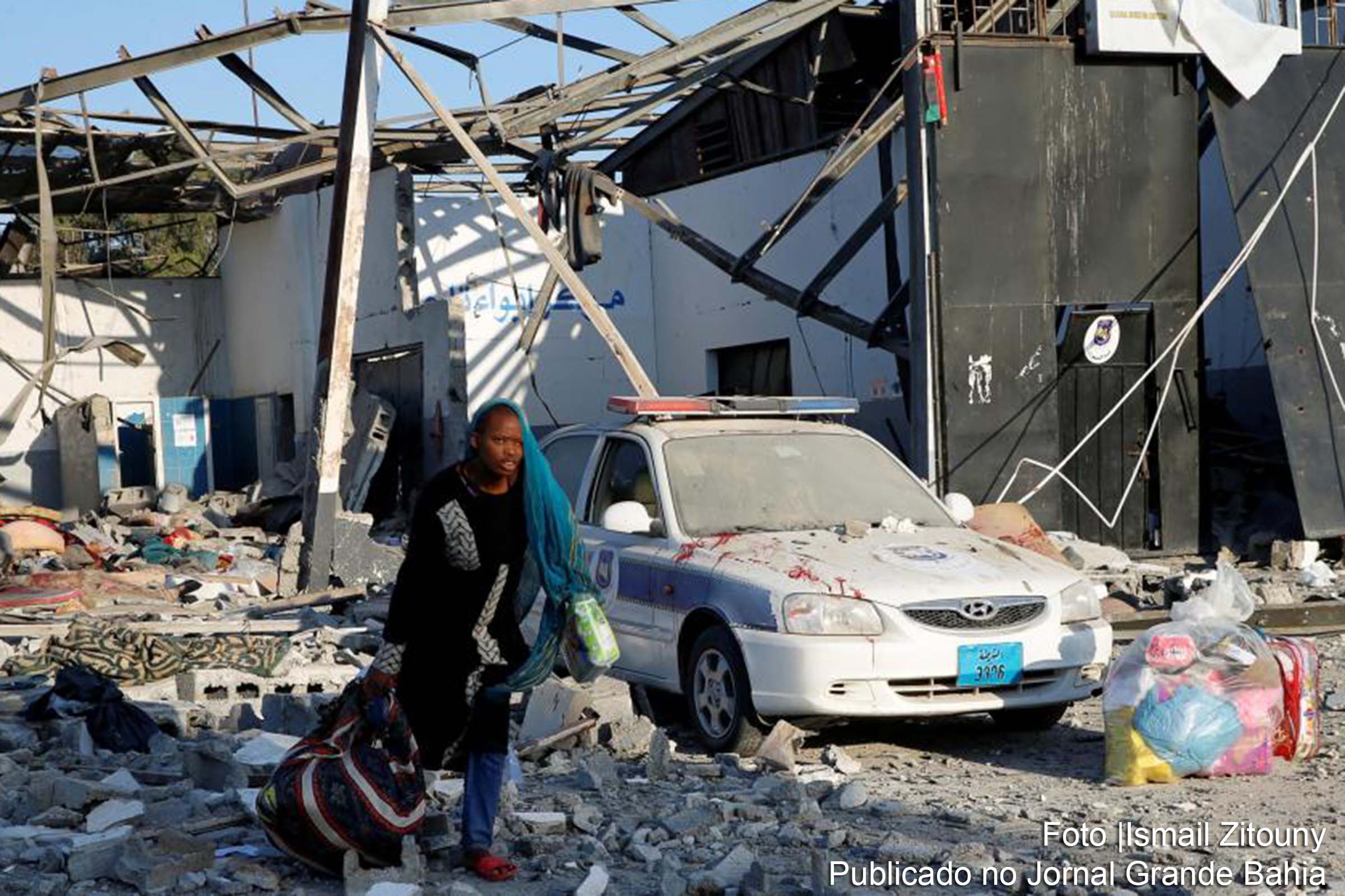 Migrante recolhe pertences no centro de refugiados de Tajura, alvo de um ataque das forças de Haftar.