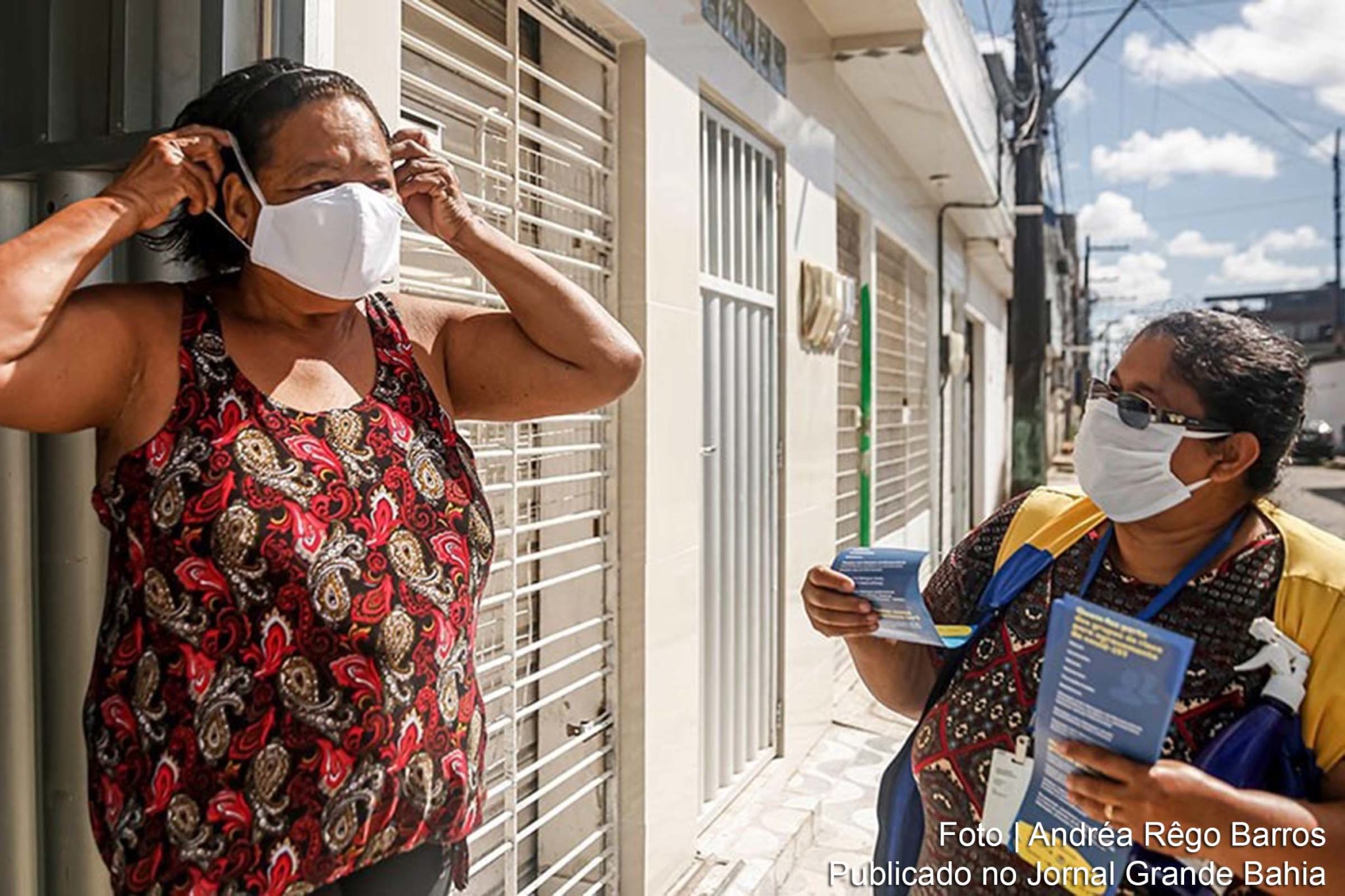 Funcionária da prefeitura de Recife instrui moradora quanto ao uso de máscara; medidas de proteção contra a covid-19 são essenciais para conter a pandemia.