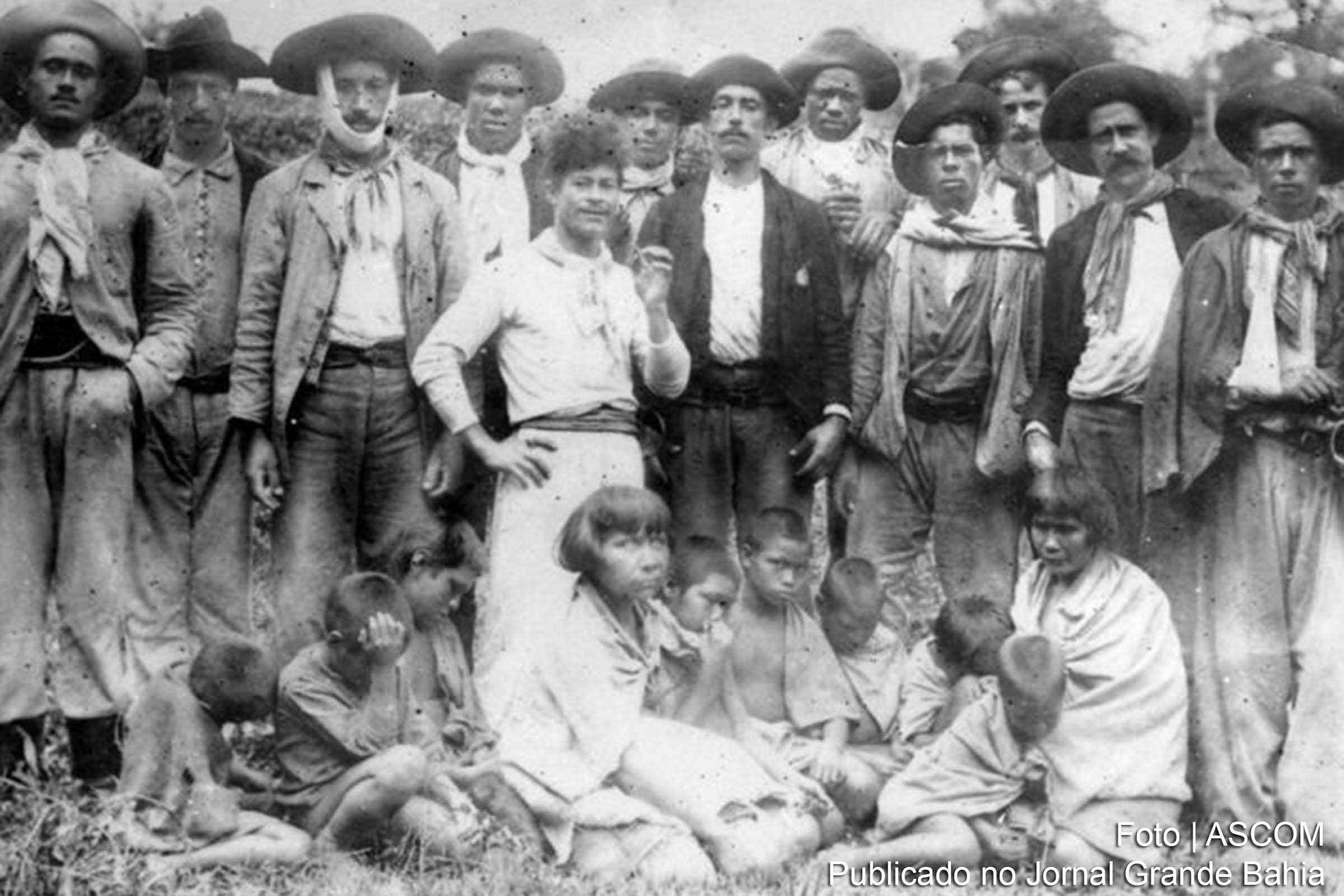 Em pé, bugreiros posam com mulheres e crianças do povo Xokleng capturadas após ataque a acampamento.