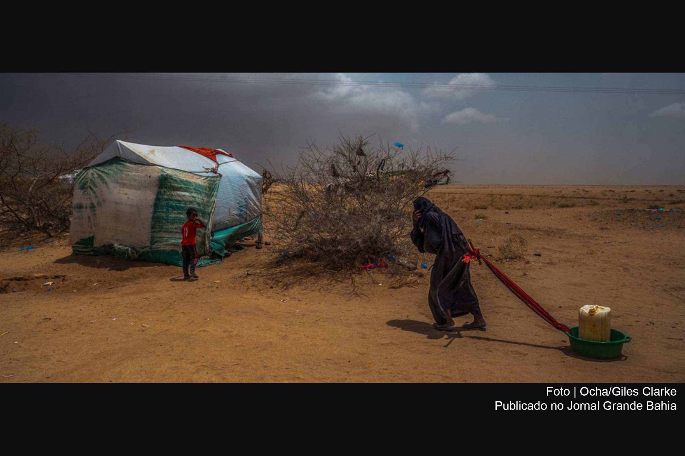 Idosa leva água para sua tenda em um campo de deslocados no norte do Iêmen, perto da fronteira com a Arábia Saudita.