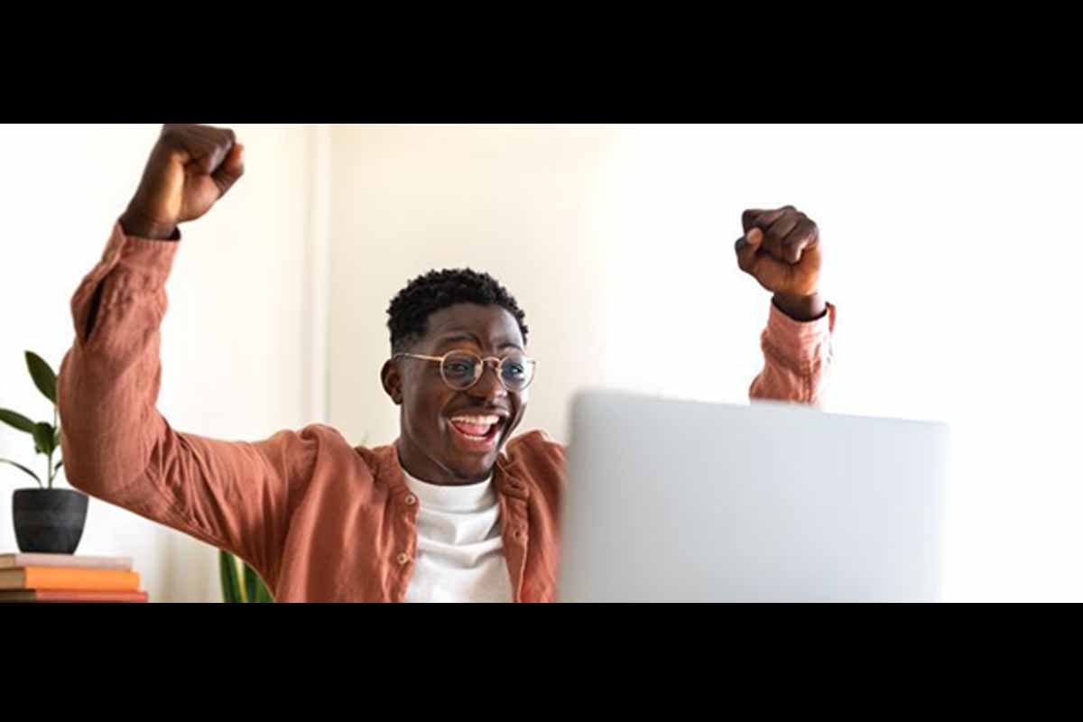 Homem olhando para tela de computador e comemorando.